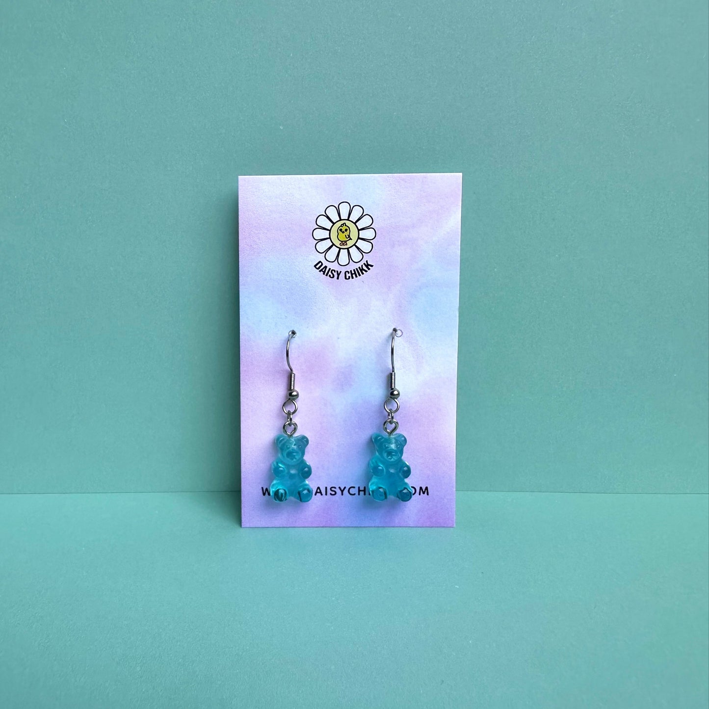 Blue gummy bear earrings on silver hooks displayed on a pastel Daisy Chikk backing card – handmade kawaii resin earrings