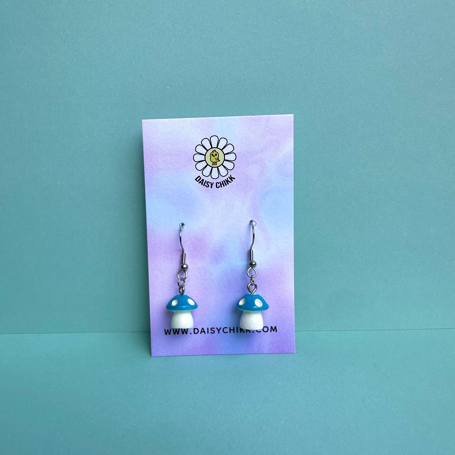 Blue mushroom earrings on pastel Daisy Chikk backing card – kawaii toadstool jewellery for cottagecore aesthetic