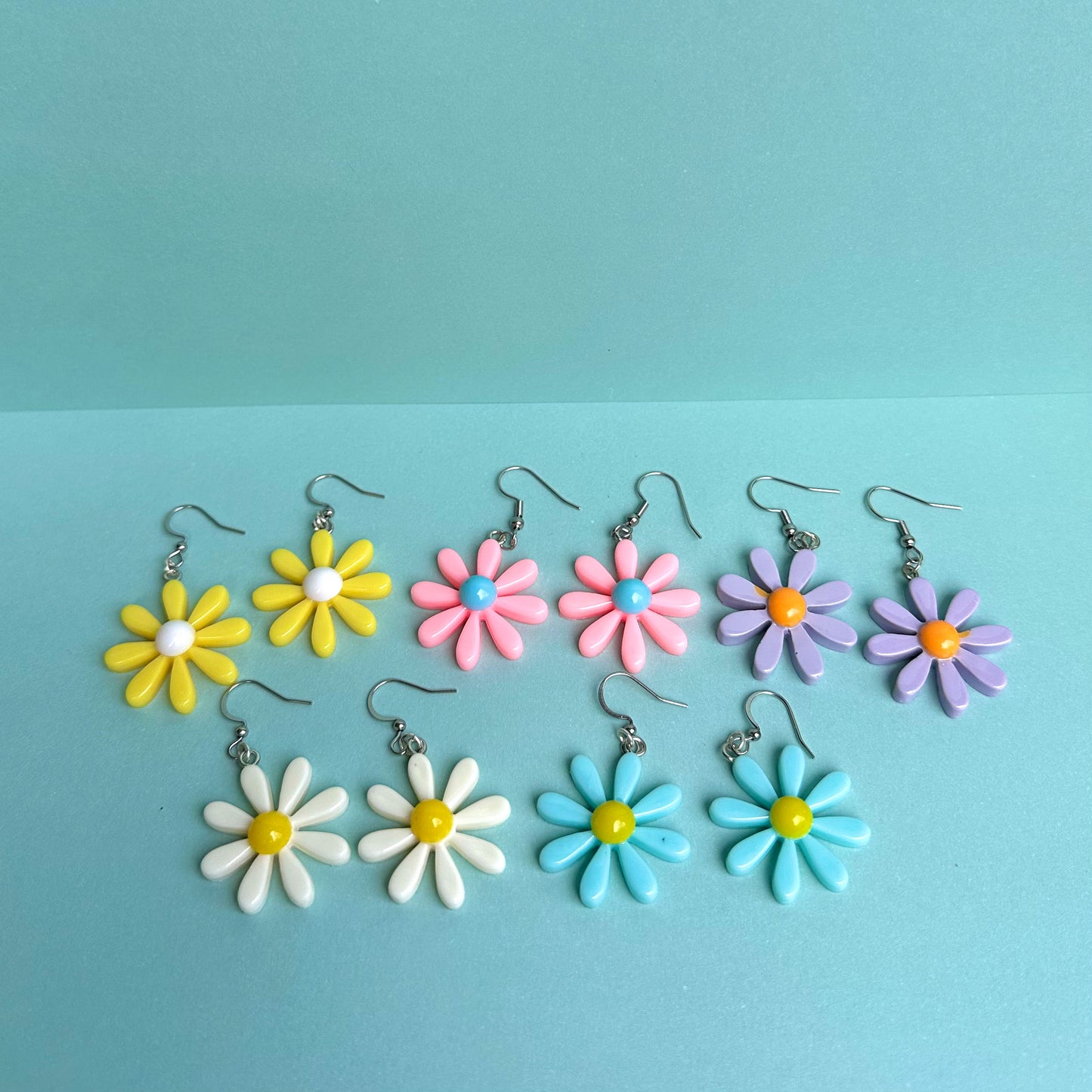 Assorted daisy earrings in pastel colours including yellow, pink, blue, purple and white with silver hooks – handmade Y2K floral statement jewellery by Daisy Chikk
