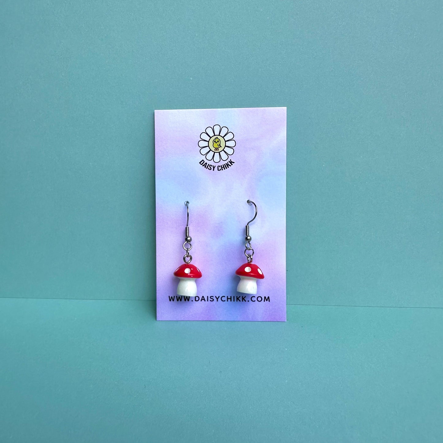 Red mushroom earrings on pastel Daisy Chikk backing card – kawaii toadstool jewellery for cottagecore aesthetic