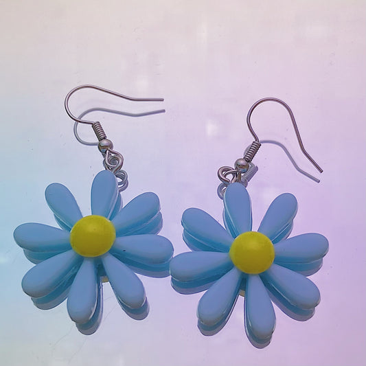 Close-up of blue daisy earrings with white centre and silver hooks on iridescent rainbow background – pastel soft girl Y2K jewellery aesthetic