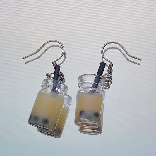 Close-up of handmade milk boba tea earrings with black straws and silver hooks – kawaii resin bubble tea jewellery