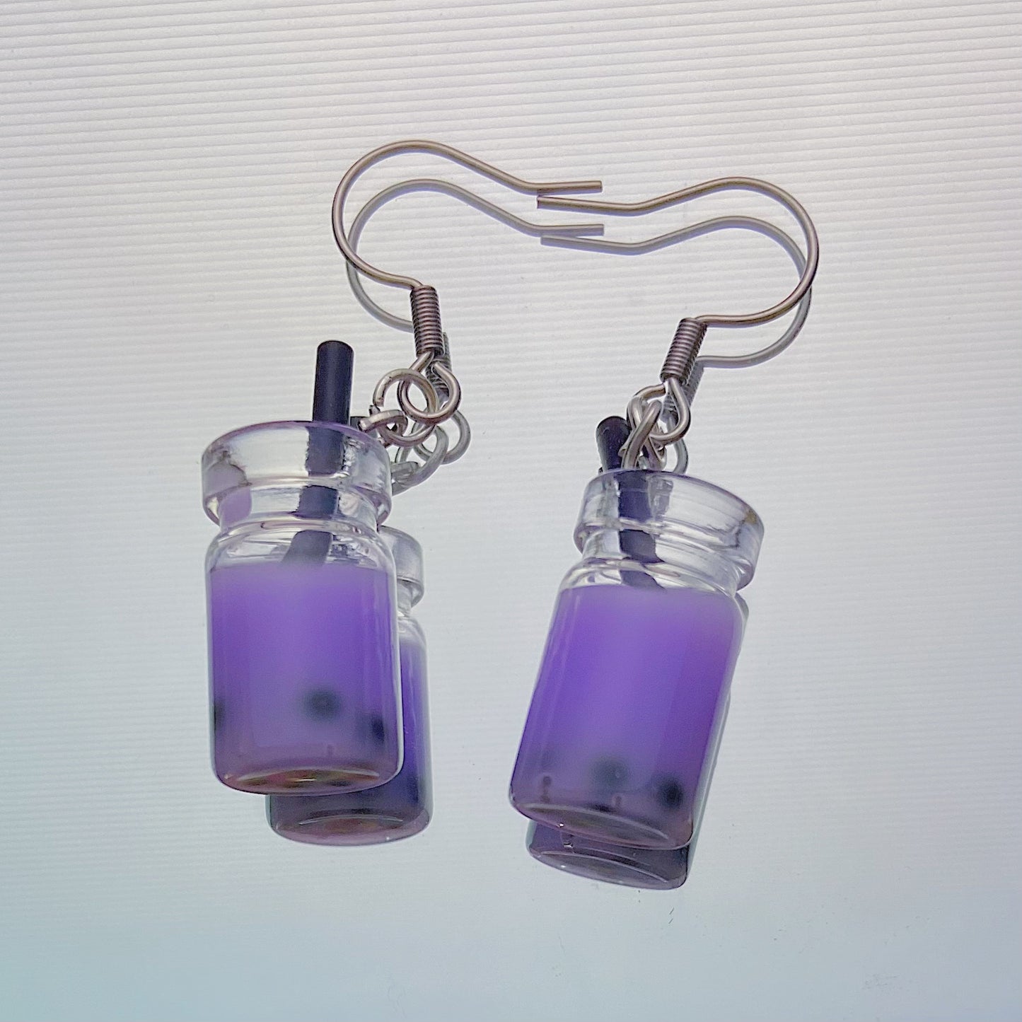 Close-up of handmade purple boba tea earrings with black straws and silver hooks – kawaii resin bubble tea jewellery