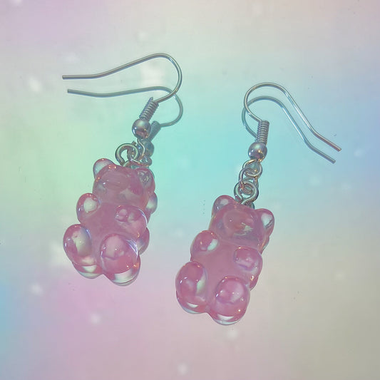 Close-up of translucent pink gummy bear earrings with silver hooks on a dreamy pastel rainbow background – kawaii Y2K handmade jewellery