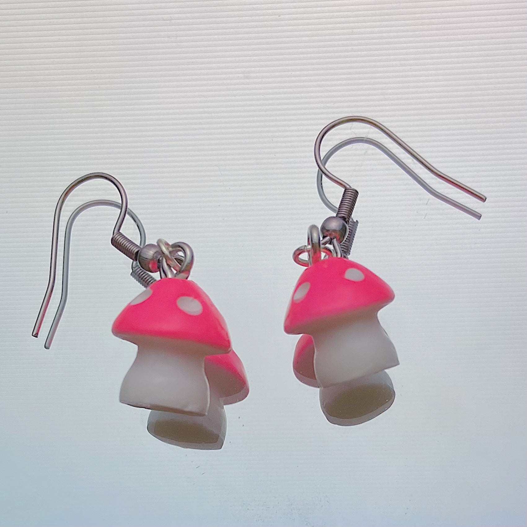 Pink mushroom earrings with white stems and silver hooks shown on a white background – handmade kawaii resin dangle jewellery, 35 x 13 mm