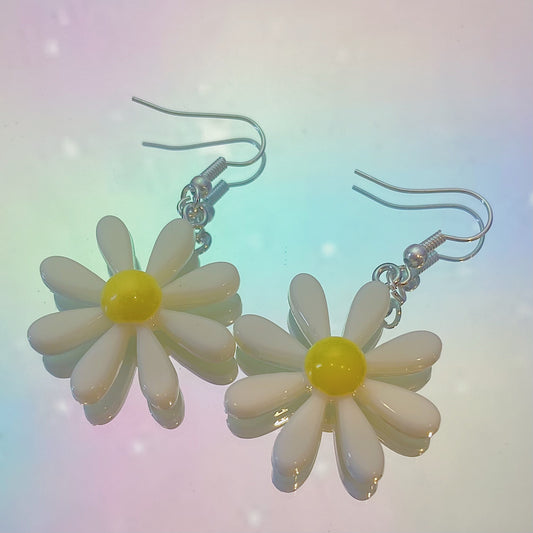 Close-up of white daisy earrings with white centre and silver hooks on iridescent rainbow background – pastel soft girl Y2K jewellery aesthetic