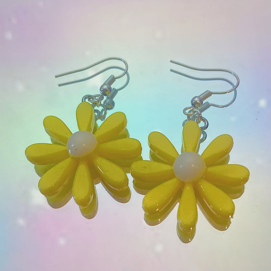 Close-up of yellow daisy earrings with white centre and silver hooks on iridescent rainbow background – pastel soft girl Y2K jewellery aesthetic