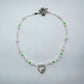 Pastel beaded necklace with faux pearls, green and pink glass beads, and a silver heart cupid charm – handmade girly fairycore jewellery by Daisy Chikk