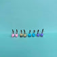 Assorted boba tea earrings in pink, beige, blue, and purple with silver hooks arranged in a row on aqua background – kawaii handmade bubble tea accessories