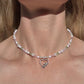 Flat lay of handmade pastel beaded necklace with pearls, green and pink crystals, and a silver cupid heart pendant – soft girl fairycore jewellery aesthetic