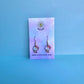 Hello Kitty earrings on Daisy Chikk pastel earring card with purple and blue ombré background – handmade Sanrio-style kawaii jewellery