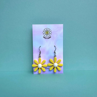 Yellow daisy flower earrings with white centre on silver hooks, displayed on pastel Daisy Chikk backing card – kawaii handmade statement jewellery