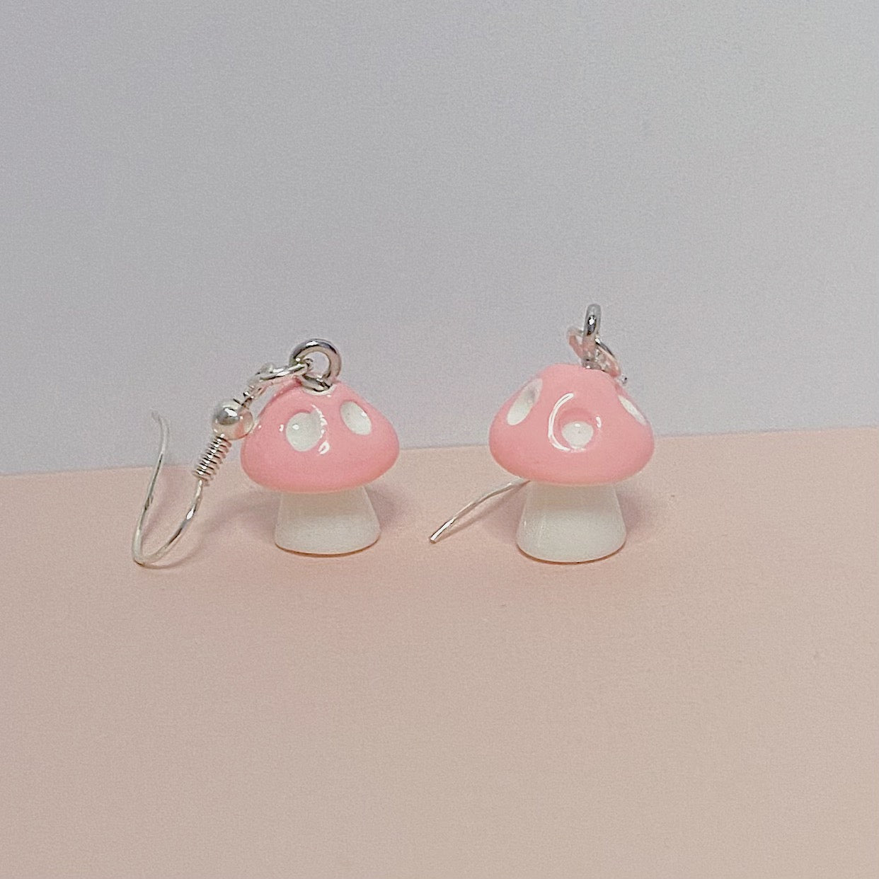 Light pink mushroom earrings with white stems and silver hooks on pastel background – kawaii fairycore handmade jewellery