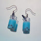 Close-up of handmade blue boba tea earrings with black straws and silver hooks – kawaii resin bubble tea jewellery