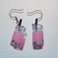 Close-up of handmade pink boba tea earrings with black straws and silver hooks – kawaii resin bubble tea jewellery